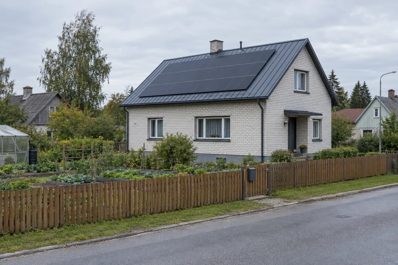 Valgete silikaattellistest seintega eramaja, mille plekk-katusel on mustad päikesepaneelid