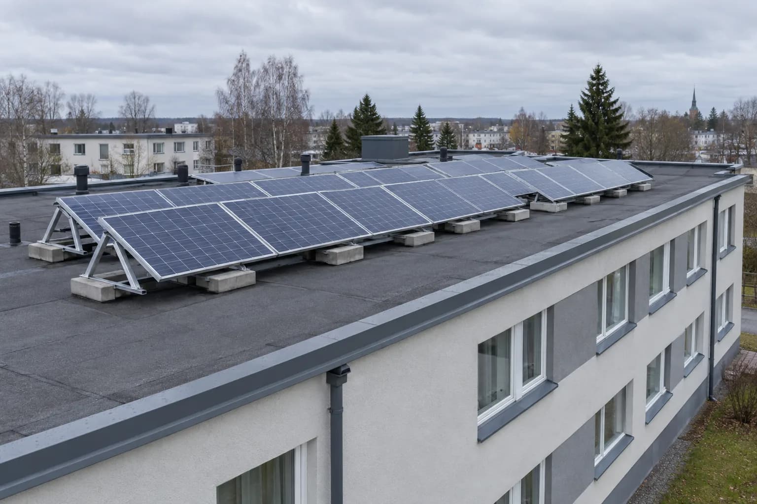 Lamekatusel kolmnurksetel alusraamidel päikesepaneelid, mida hoiavad paigal betoonraskused